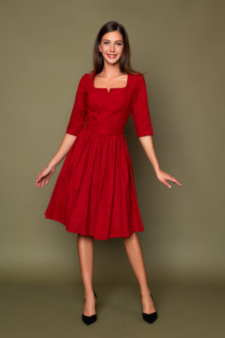 Μίντι κόκκινο φόρεμα με τετράγωνο μπούστο και 3/4 μανίκια, σε μεσάτη γραμμή, με σούρα στη φούστα, που κλείνει πίσω με κρυφό φερμουάρ.