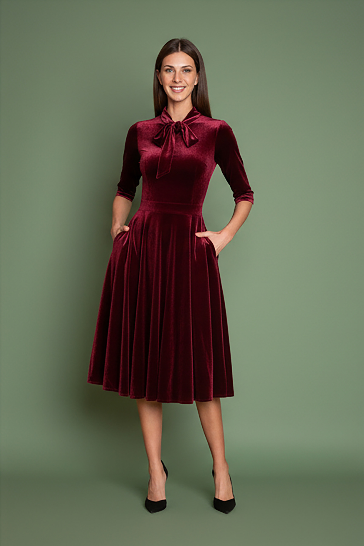 mpornto-veloudo-2 Μπορντό φόρεμα, εμπνευσμένο από τη λάμψη της δεκαετίας του 1950, από πολυτελές απαλό βελούδο, με κολακευτική λαιμόκοψη V που τονίζεται από έναν γοητευτικό φιόγκο από ύφασμα που δένει μπροστά. Οι ώμοι με την ελαφριά σούρα και τα 3/4 μανίκια προσθέτουν μια vintage πινελιά, ενώ η σταθερή ζώνη αγκαλιάζει τη σιλουέτα για ένα θηλυκό σχήμα. Σχεδιασμένο με κρυφές τσέπες με πλαϊνές ραφές και φούστα σε κλος γραμμή που κινείται με χάρη σε κάθε βήμα. Ιδανικό για επίσημες περιστάσεις ή απλώς για να αγκαλιάσει το κλασικό στυλ με μια μοντέρνα πινελιά.