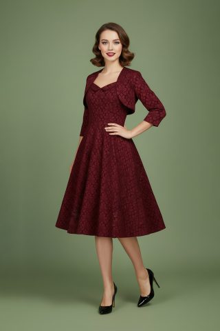 Μίντι κλος φόρεμα με μπολερό, εμπνευσμένο από το vintage στυλ, σε μια πλούσια απόχρωση κρασιού και διακοσμημένο με ένα εξαιρετικό ανάγλυφο φλοράλ print. Το κολακευτικό εφαρμοστό μπούστο τονίζει τη μέση, και καταλήγει σε μια φαρδιά φούστα για χαριτωμένη κίνηση. Ένα εκλεπτυσμένο ντεκολτέ με πέτο προσθέτει μια πινελιά ρετρό γοητείας, ενώ το ασορτί μπολερό που περιλαμβάνεται ολοκληρώνει την sophisticated εμφάνιση. Ιδανικό για επίσημες περιστάσεις ή για μια κομψή δήλωση οποιαδήποτε μέρα της εβδομάδας.