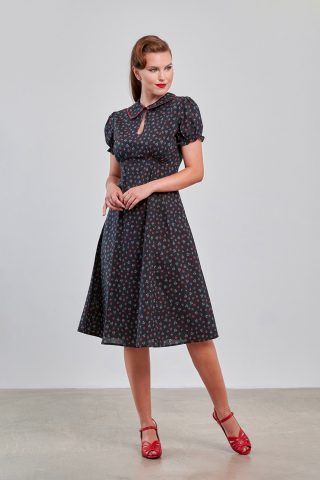 40s vintage φόρεμα, με απαράμιλλη σοφιστικέ αισθητική, που ξεχωρίζει για τον πανέμορφο κυματιστό γιακά σε χρωματική αντίθεση και το ιδιαίτερο άνοιγμα στο ντεκολτέ που κλείνει με κουμπί. Η κλασική fit & flare γραμμή του αγκαλιάζει τη σιλουέτα, ενώ τα κοντά, ελαστικά μανίκια με λεπτομέρειες από βολάν προσθέτουν μια επιπλέον δόση ρομαντισμού. Κατασκευασμένο από 100% φυσικό βαμβάκι, είναι το ιδανικό φόρεμα για να παραμείνετε κομψή και δροσερή καθ' όλη τη διάρκεια του καλοκαιριού.
