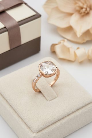 Ένα εντυπωσιακό δαχτυλίδι που αιχμαλωτίζει το φως με κάθε κίνηση. Στο κέντρο του δεσπόζει ένας μεγάλος, πεντακάθαρος κρύσταλλος σε κοπή cushion-cut, ο οποίος αναδεικνύεται από τη ροζ-χρυσή βάση και τις επιπλέον λαμπερές λεπτομέρειες στην αλυσίδα του δαχτύλου.