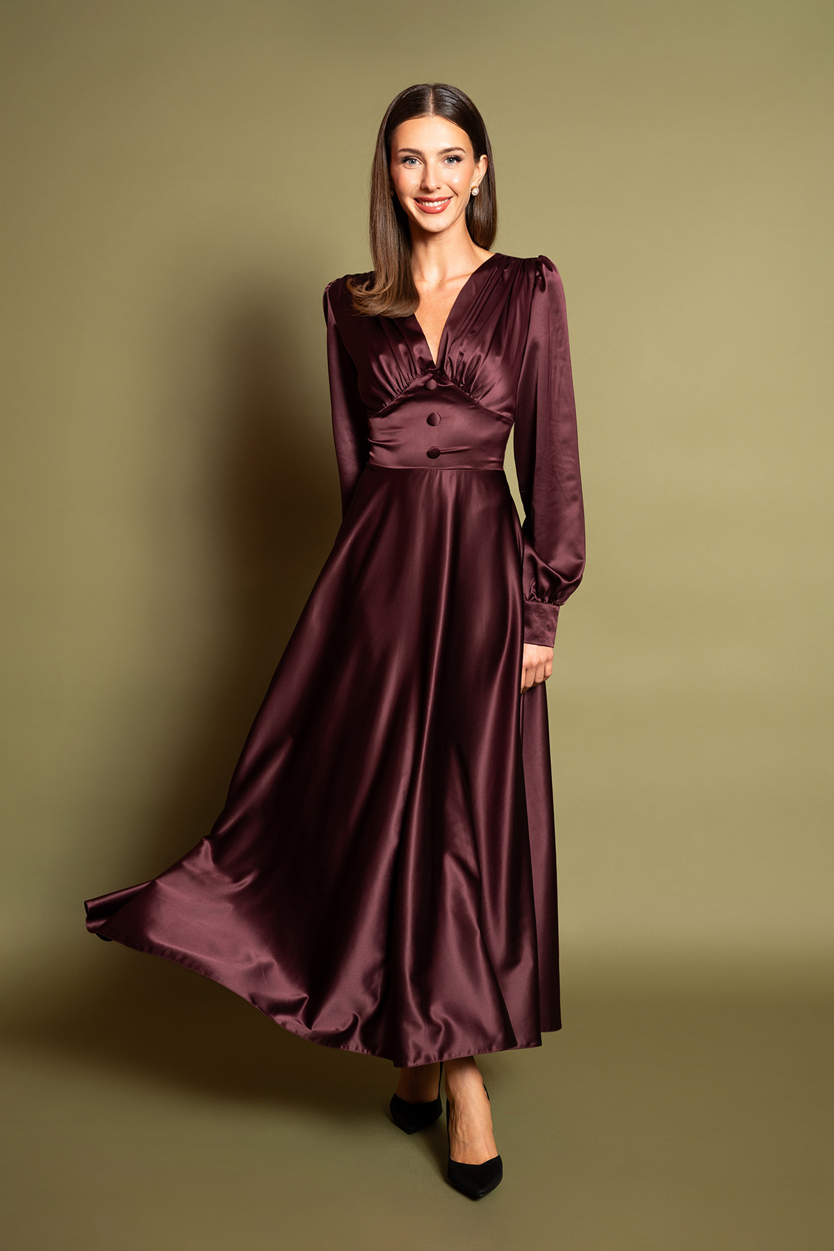 plum-saten-midi-forema-4 Ανακαλύψτε την απόλυτη πολυτέλεια με ένα plum σατέν μίντι φόρεμα. Διαθέτει θηλυκή V λαιμόκοψη, σούρες στο στήθος, μακριά μανίκια και διακοσμητικά ντυμένα κουμπιά στη μέση. Η αέρινη κλος φούστα χαρίζει κίνηση και διαχρονική ρετρό κομψότητα σε κάθε επίσημη εμφάνιση.
